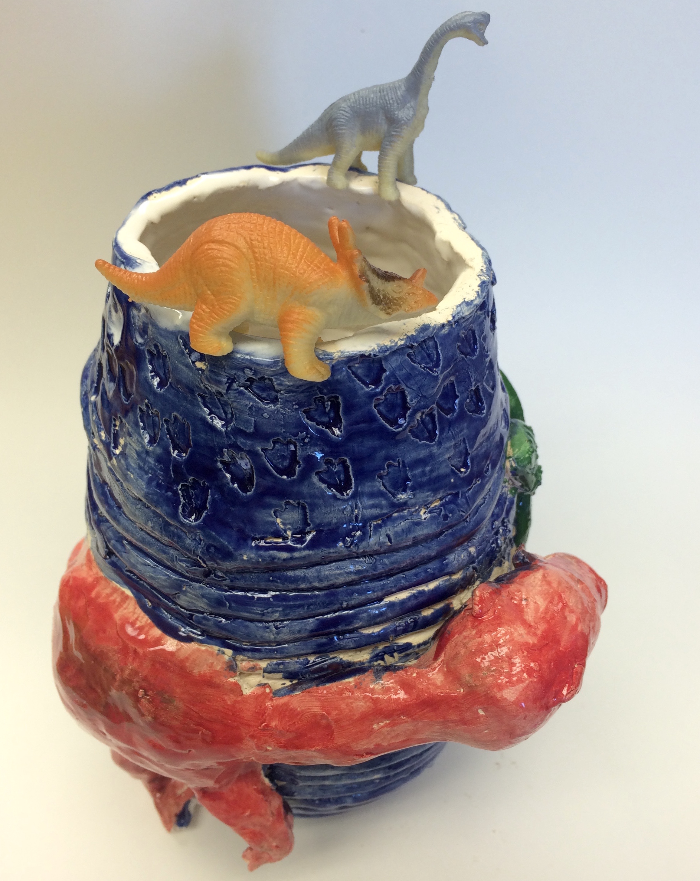 dinosaurs sitting on top of a ceramic pot