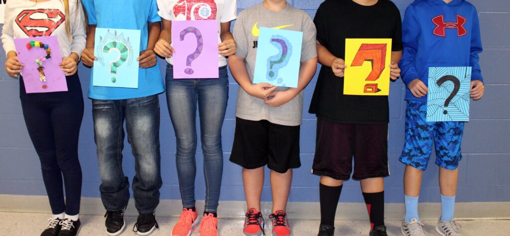 students holding question mark signs