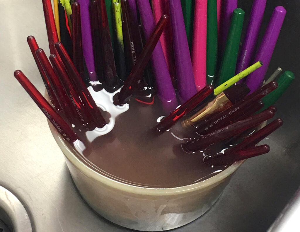 paintbrushes in water cup