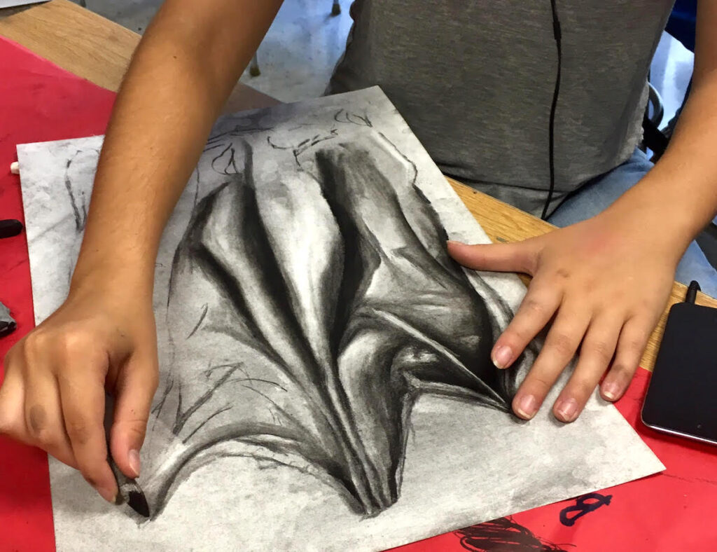 student working on charcoal drawing