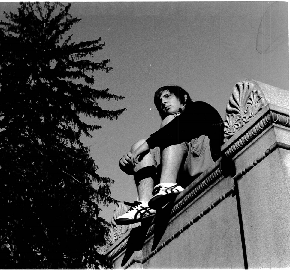 black and white photo of student sitting on a ledge