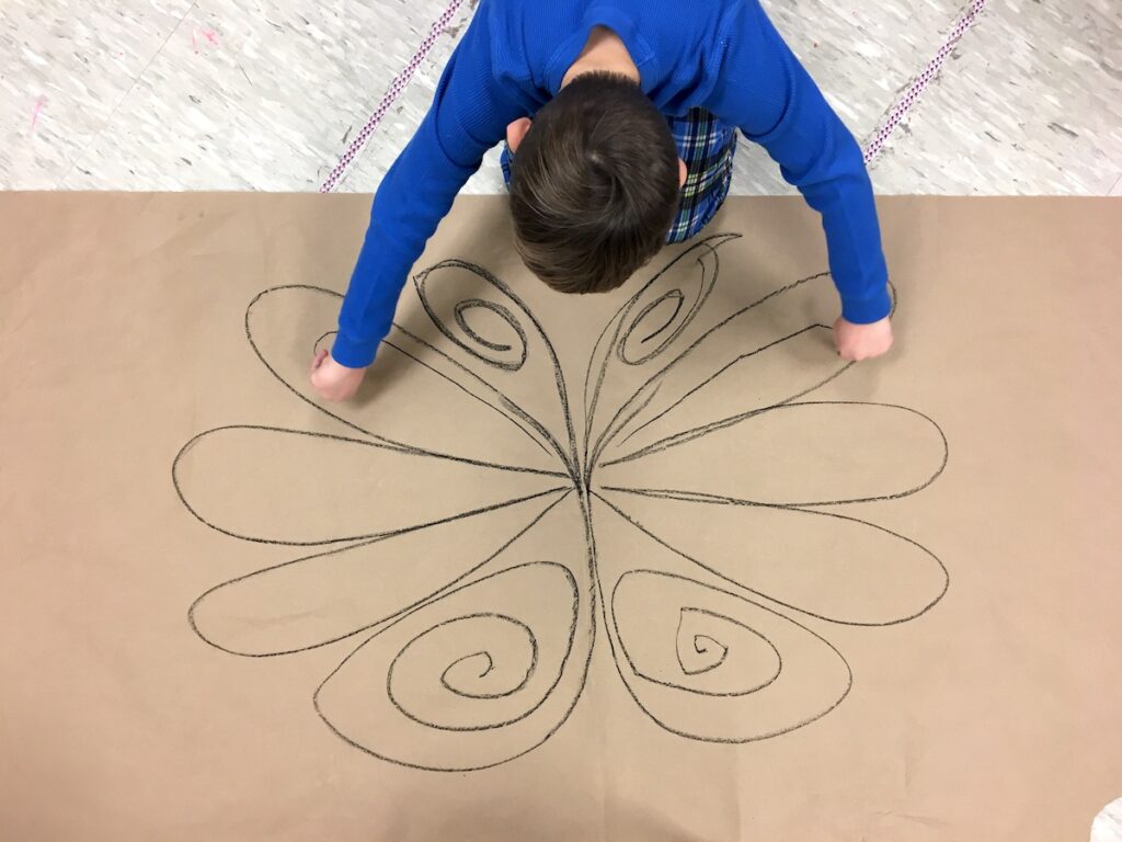 student drawing on large paper with both hands
