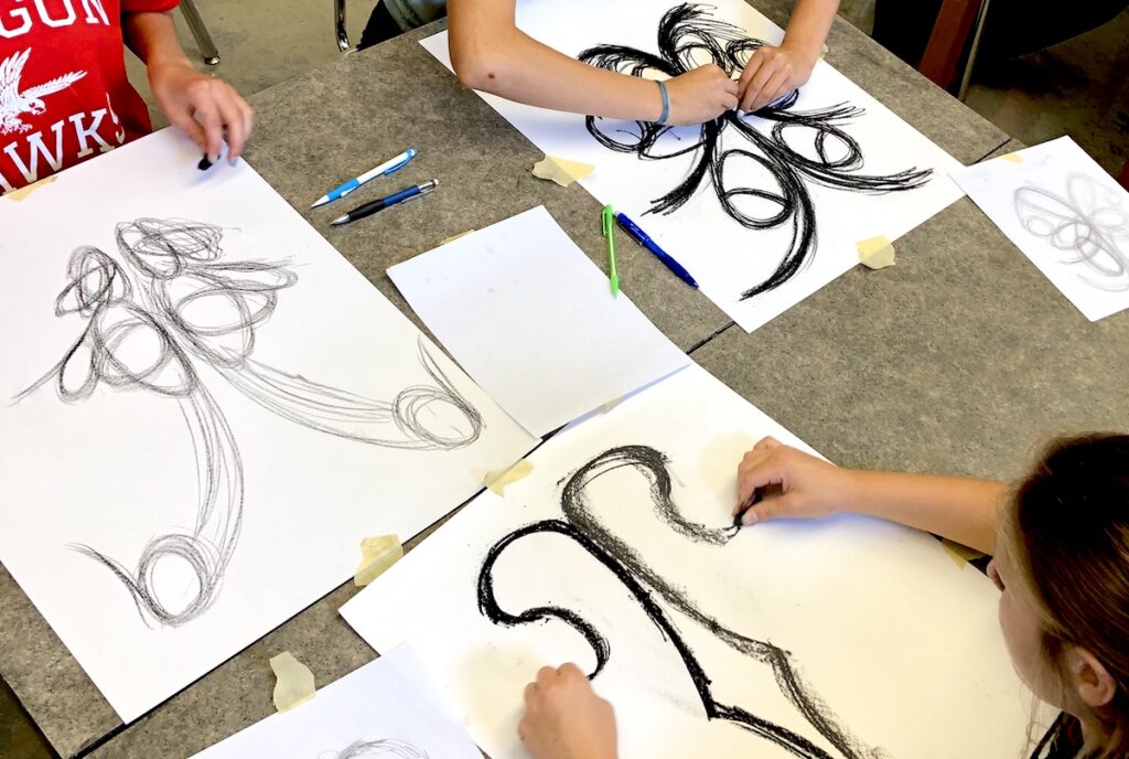 Students doing symmetrical charcoal drawings