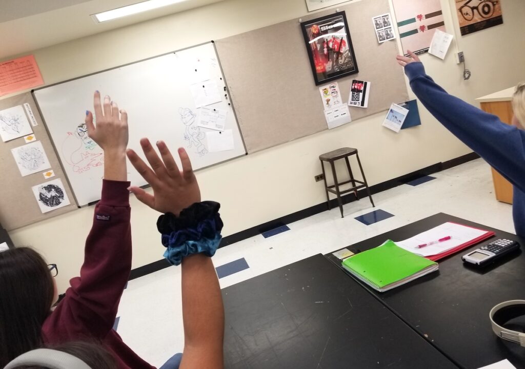 Students in a classroom with their hands raised