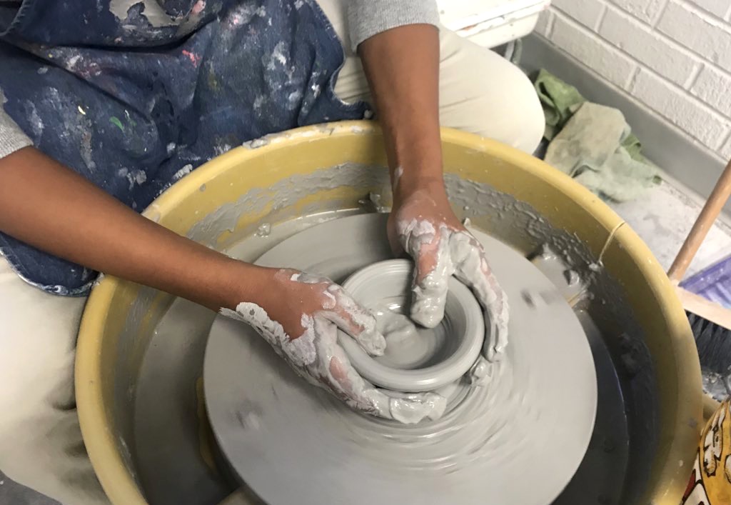 student working on a wheel with clay