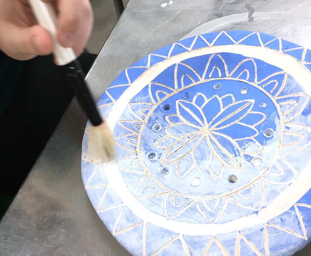 student glazing a radial floral design
