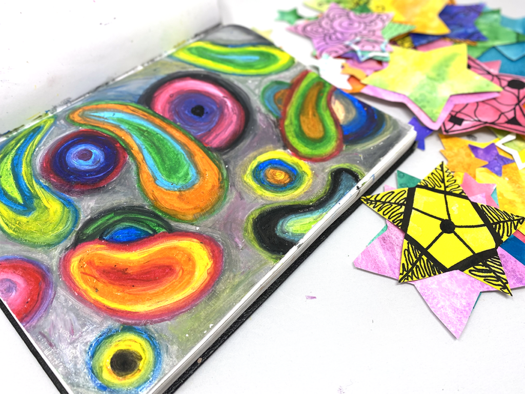 abstract oil pastel design in sketchbook with paper stars