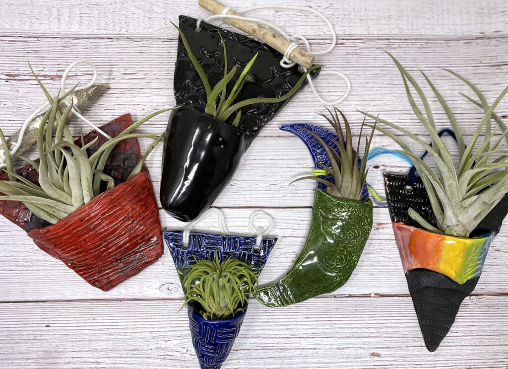 five ceramic slab planters with air plants on a table
