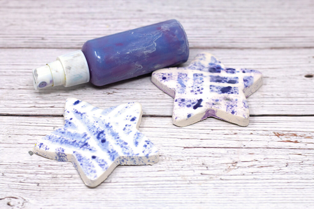 two white ceramic stars with blue spray and small spray bottle