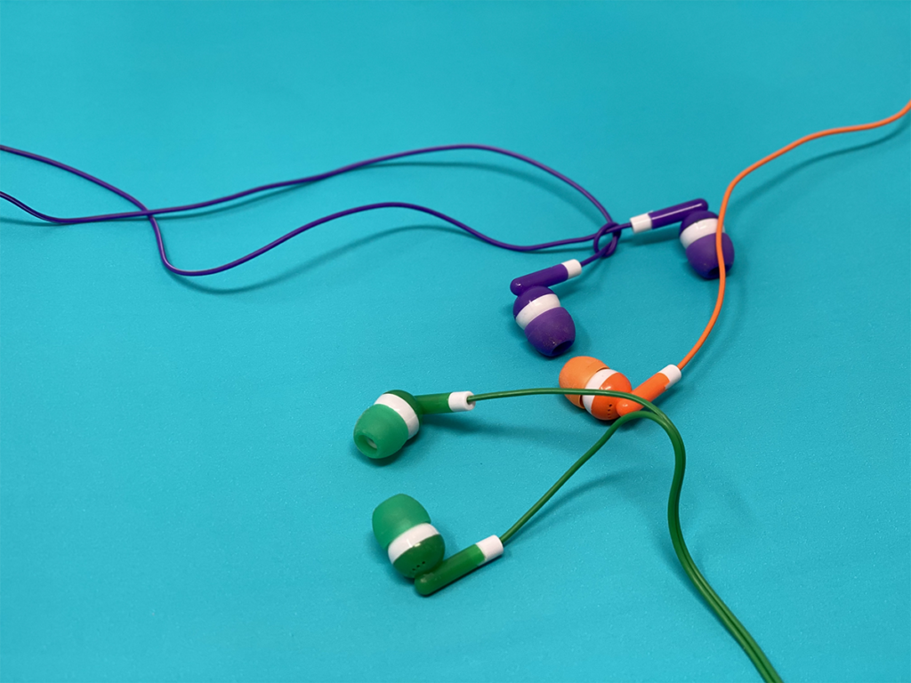 three colored earbuds headphones on teal background