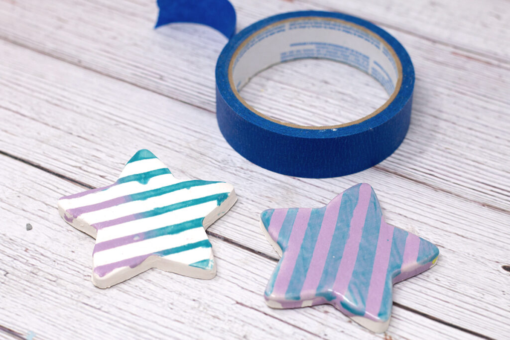two completed ceramic stars with stripes and roll of blue masking tape