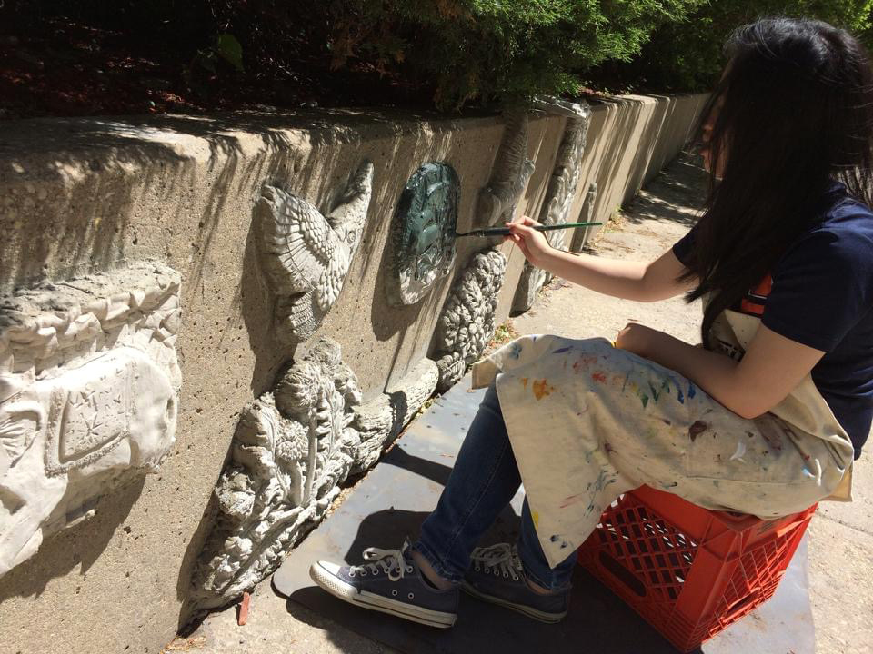 student painting concrete wall relief