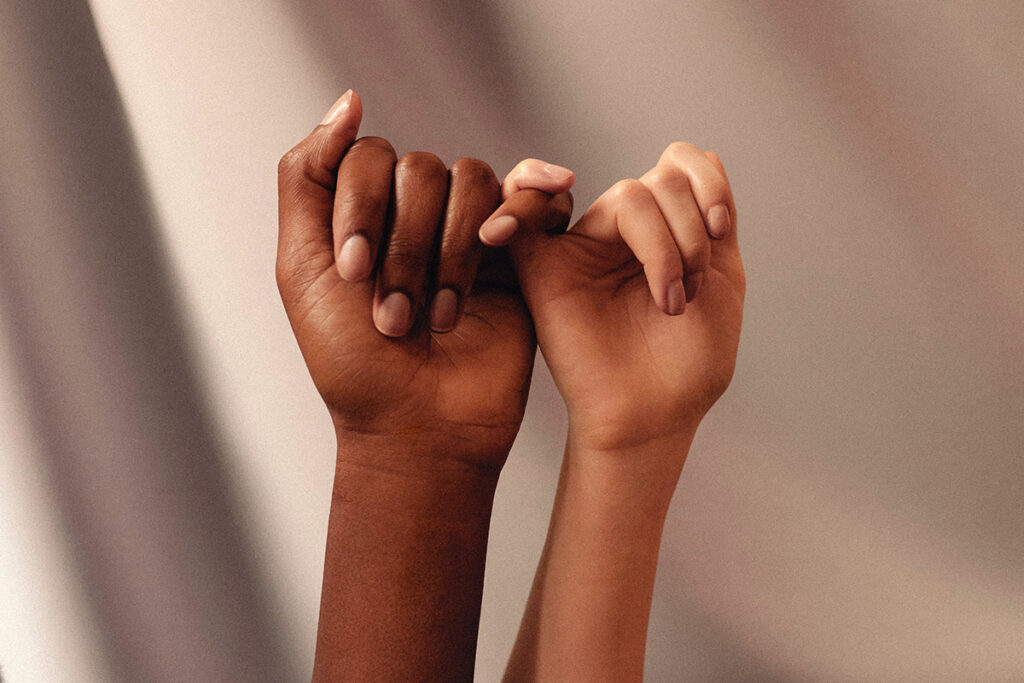 two hands with different skin colors pinkies linked