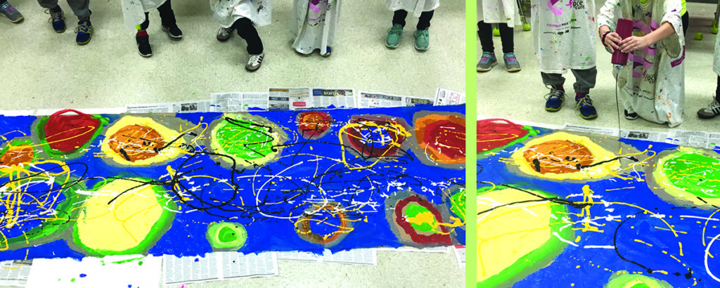 students squeezing paint on large paper on floor