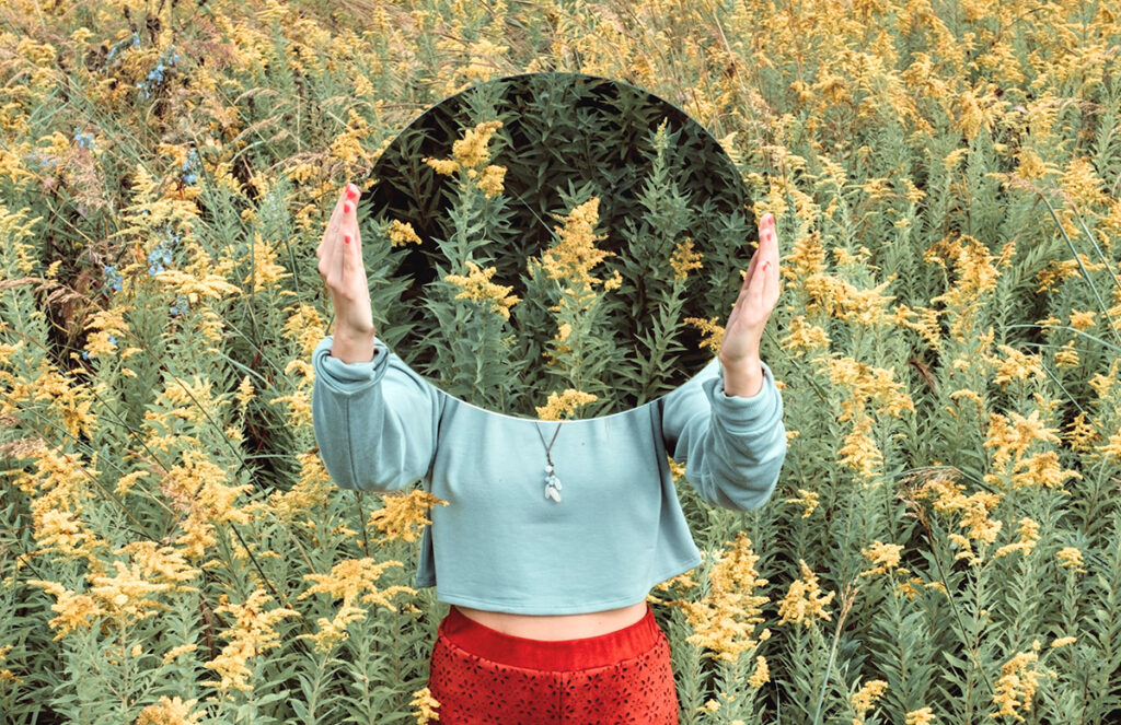 girl holding mirror in field