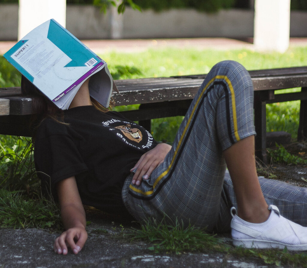 student with book on face