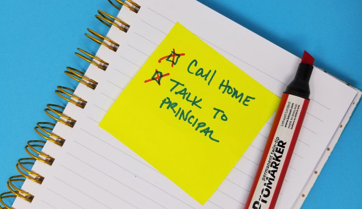 Image of a post-it note with call home and talk to principal