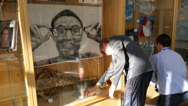 student putting work into display case