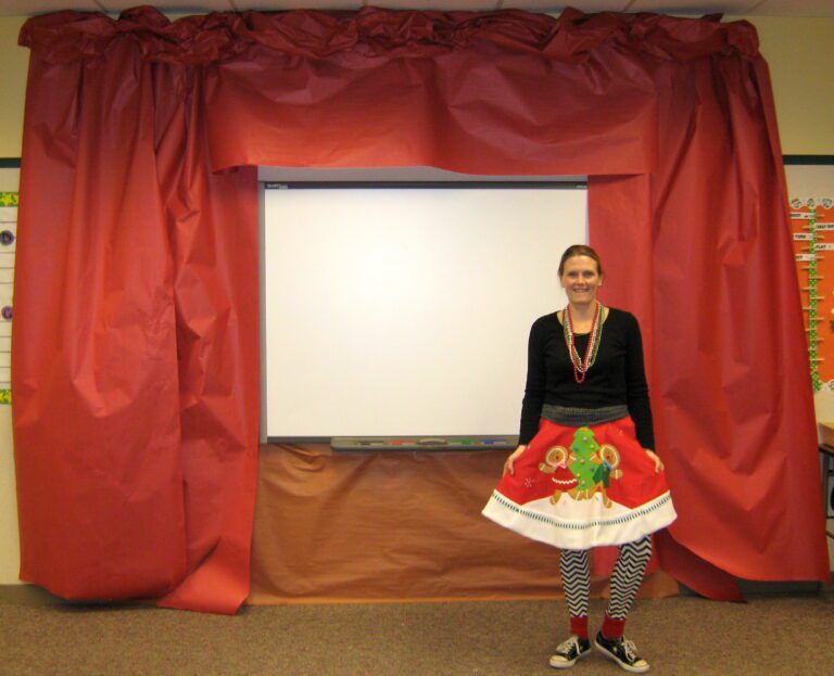 teacher in Christmas outfit standing in front of a stage