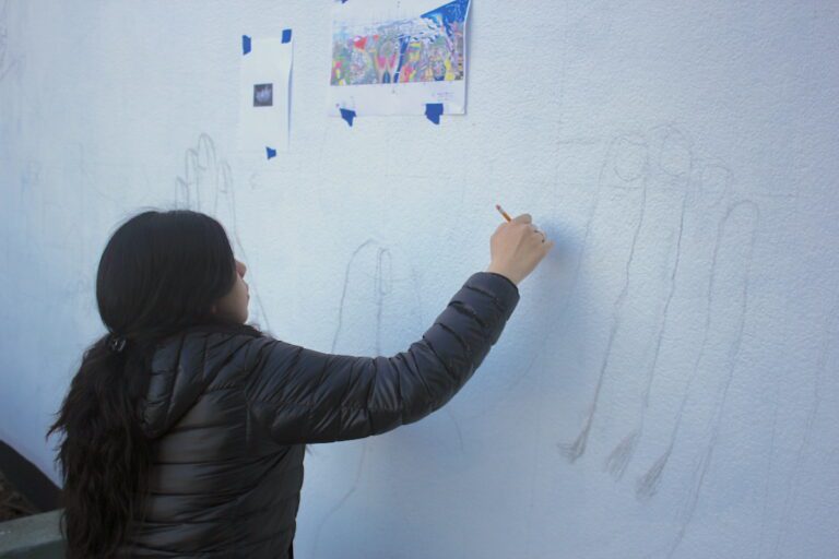 student drawing large on a wall