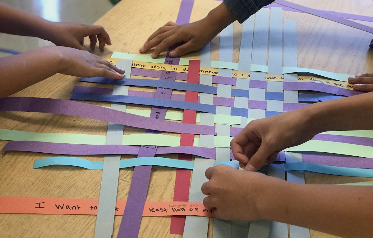 students weaving paper together