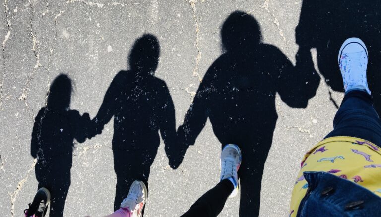 Image of the shadows of an adult holding hands with children