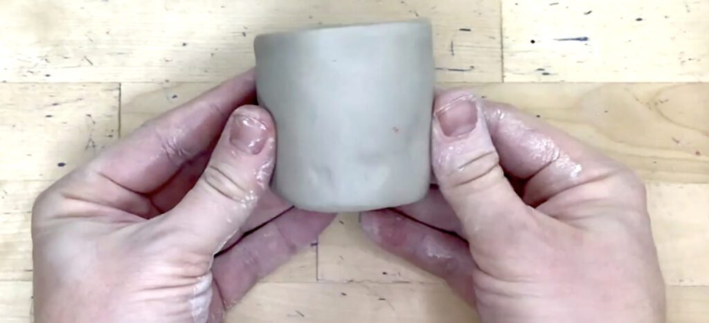 hands holding clay cylinder