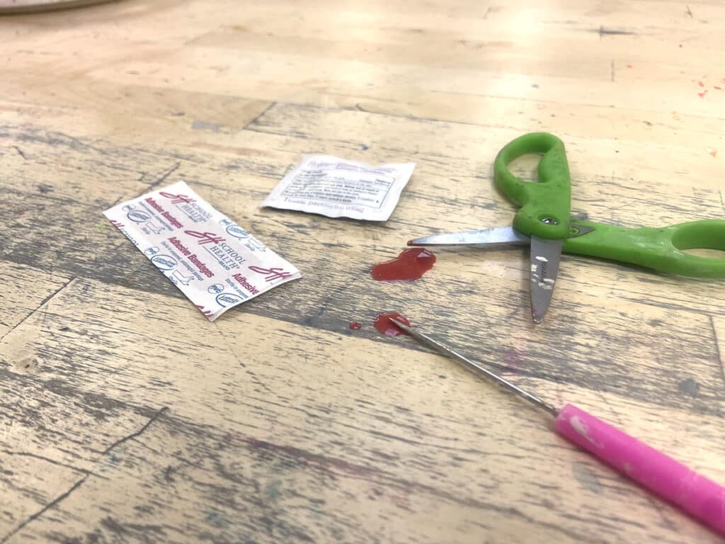 scissors and bandaid with blood on an art table