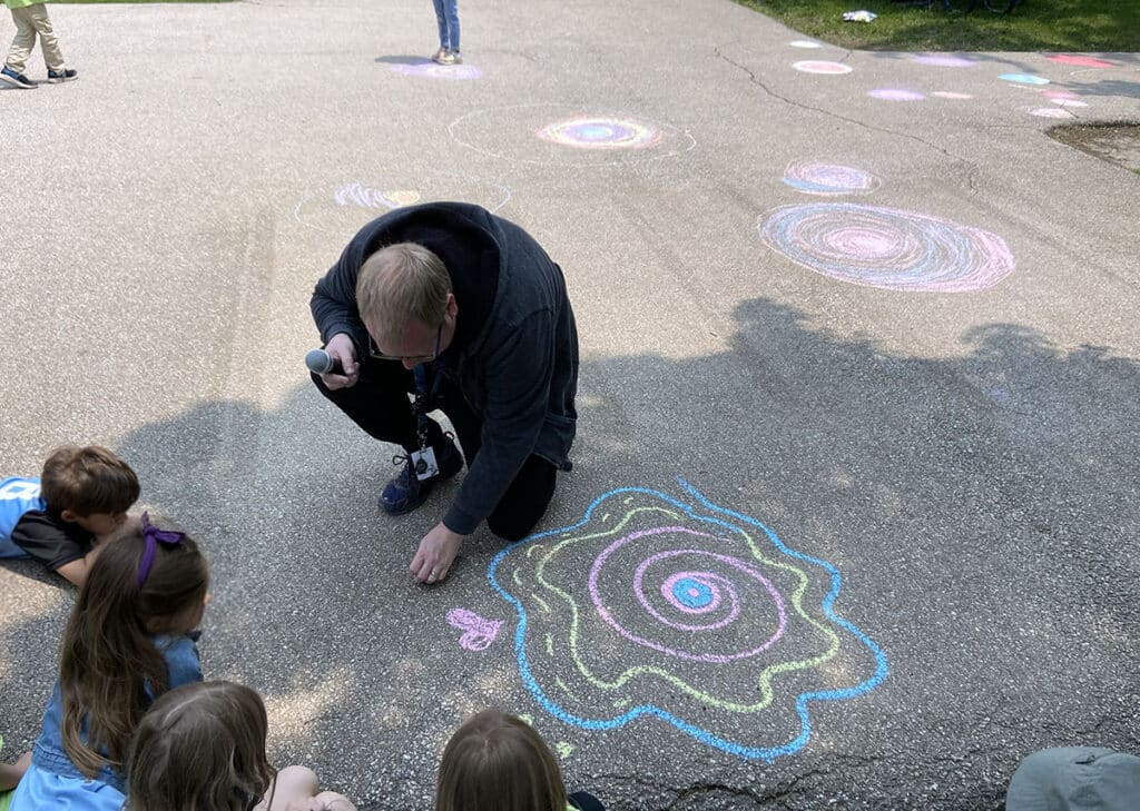 teacher making sidewalk chalk art with students