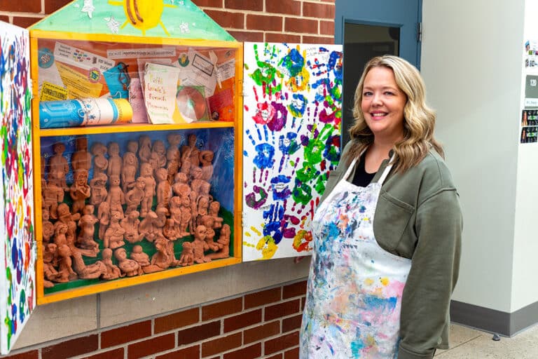art teacher in front of a hall display