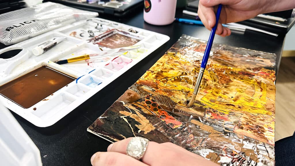 student collaging with a brush