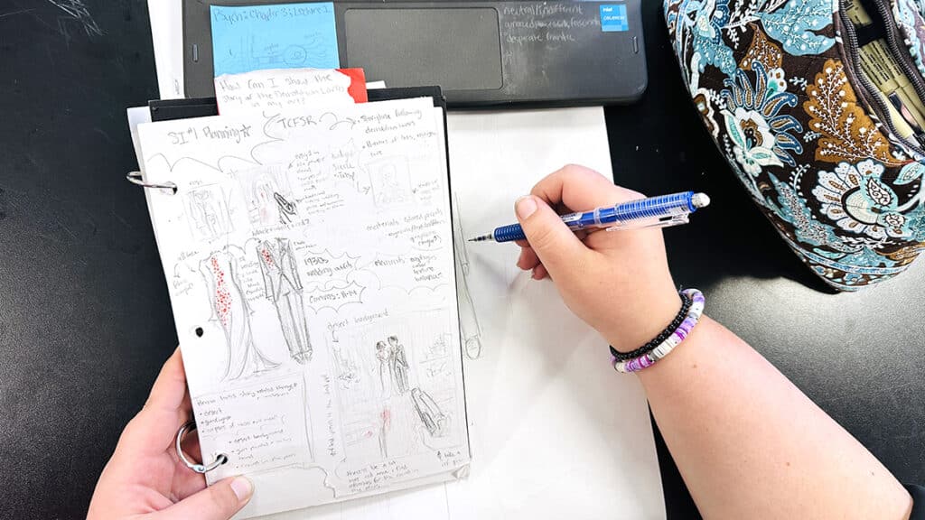 hand holding a sketchbook with thumbnail sketches