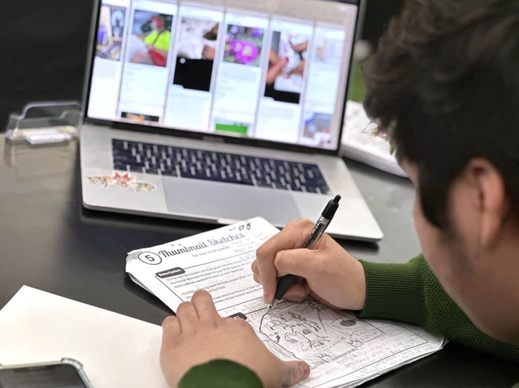 student sketching with padlet behind him