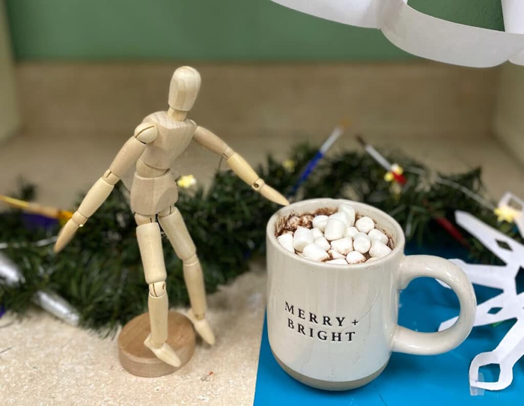 mug of hot cocoa with a wooden mannequin