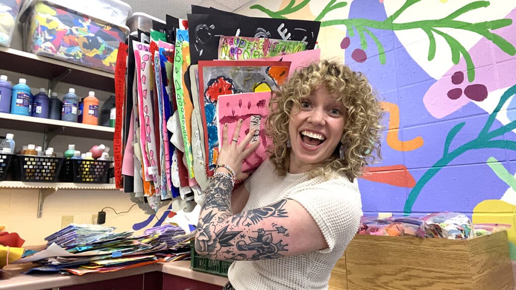 sarah krajewski holding a pile of artwork