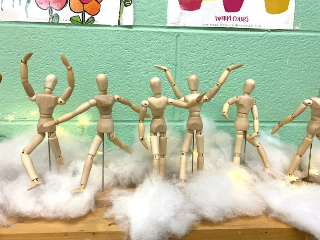 wooden mannequins with faux snow and twinkle lights