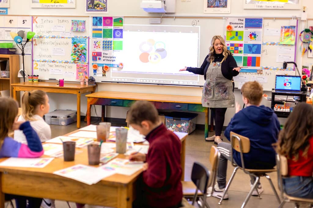 art teacher at the front of the art room talking with a student in front of the class