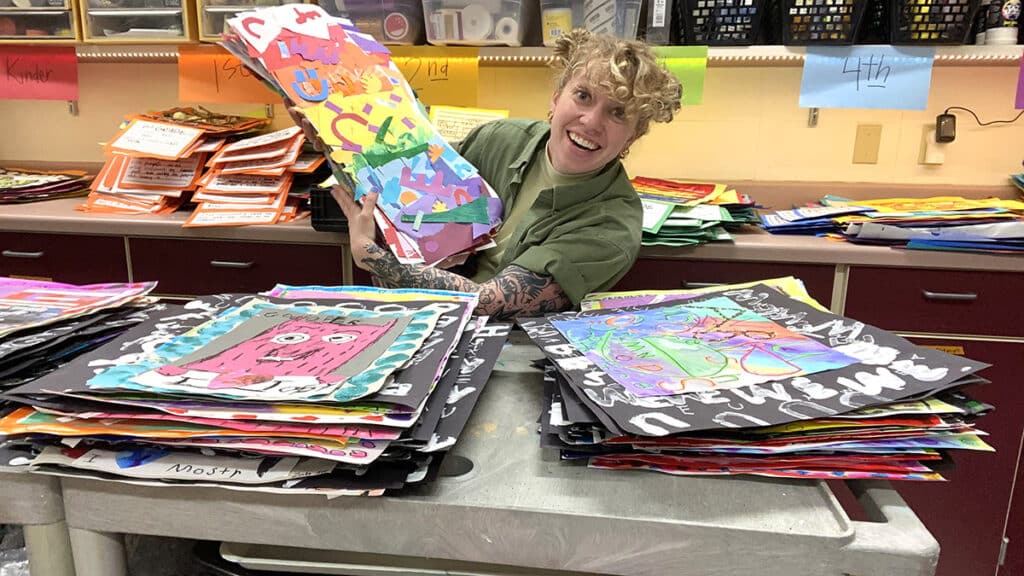 sarah holding artwork with piles in front of her