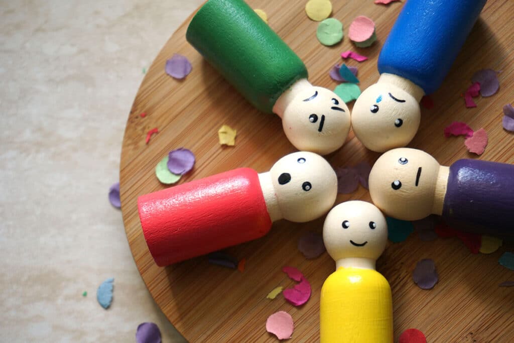 wooden figures painted rainbow colors with facial expressions