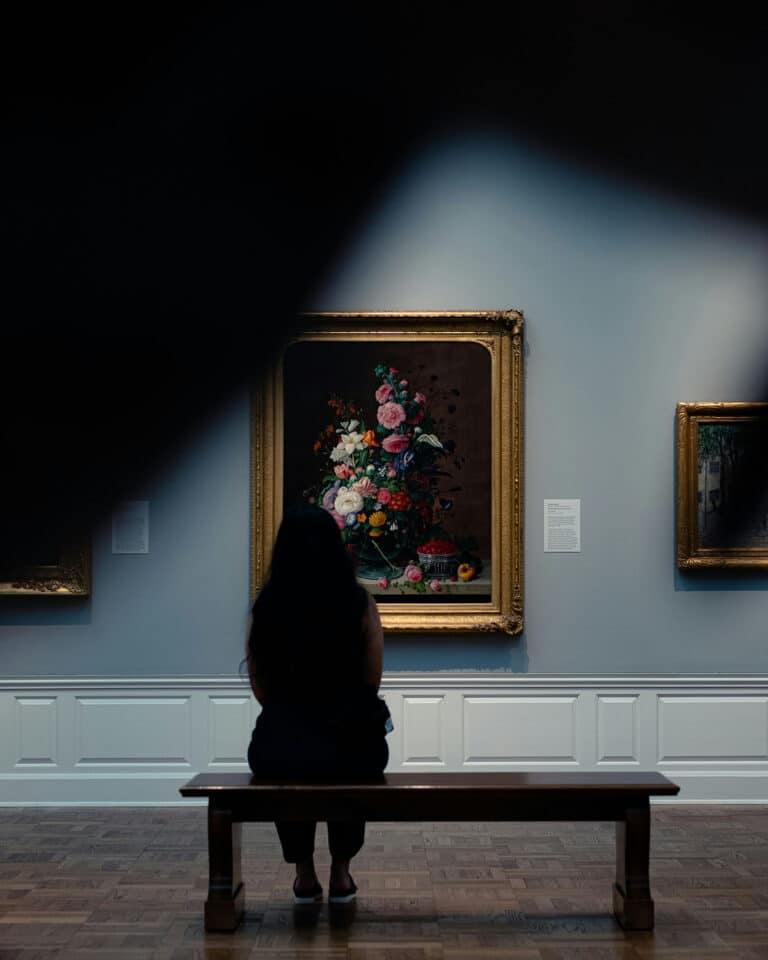 person looking at floral painting at art museum