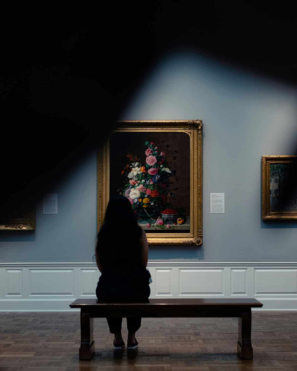 person looking at floral painting at art museum