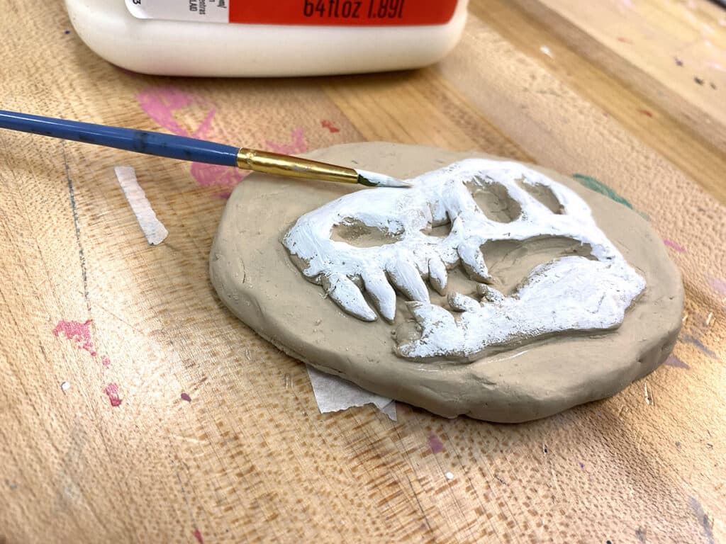 relief that looks like a fossil and animal skull with paintbrush and white paint