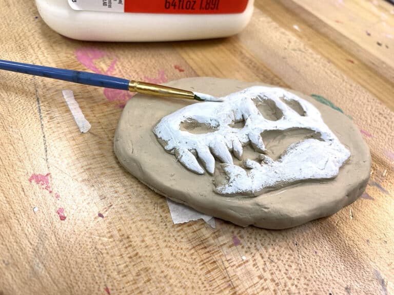 relief that looks like a fossil and animal skull with paintbrush and white paint