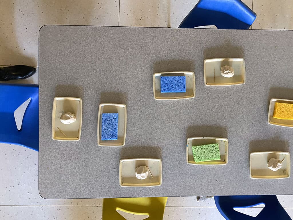 art room table setup with trays, sponges, and air-dry clay
