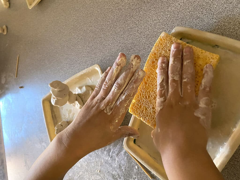 hands with air-dry clay dust and a wet sponge