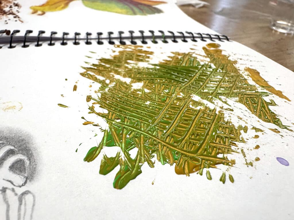 green paint in a sketchbook with toothpick scratches