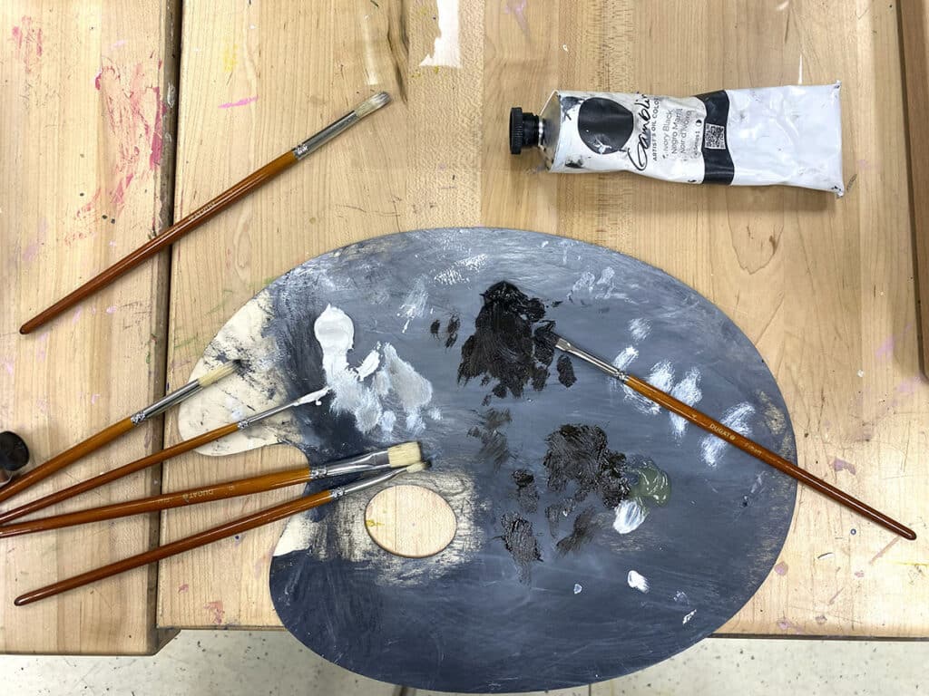 palette with brushes and black and white paint