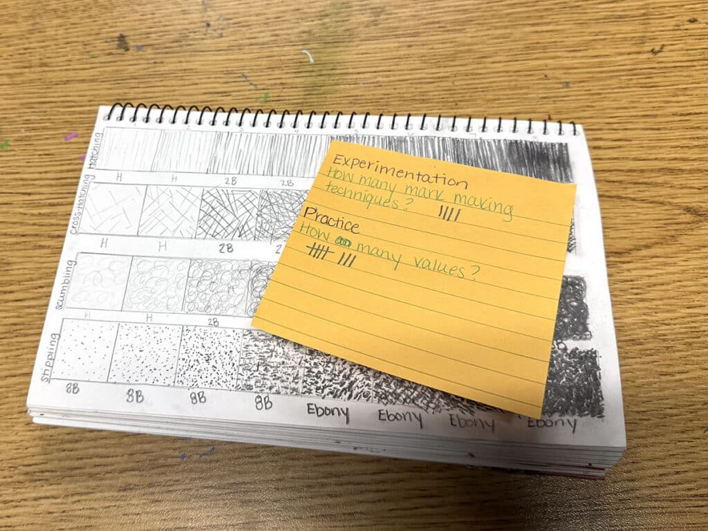 sketchbook with value scales and sticky note with data