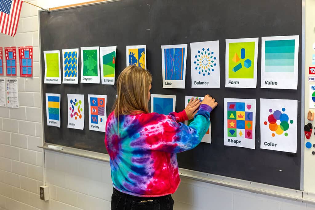teacher putting up elements and principles posters