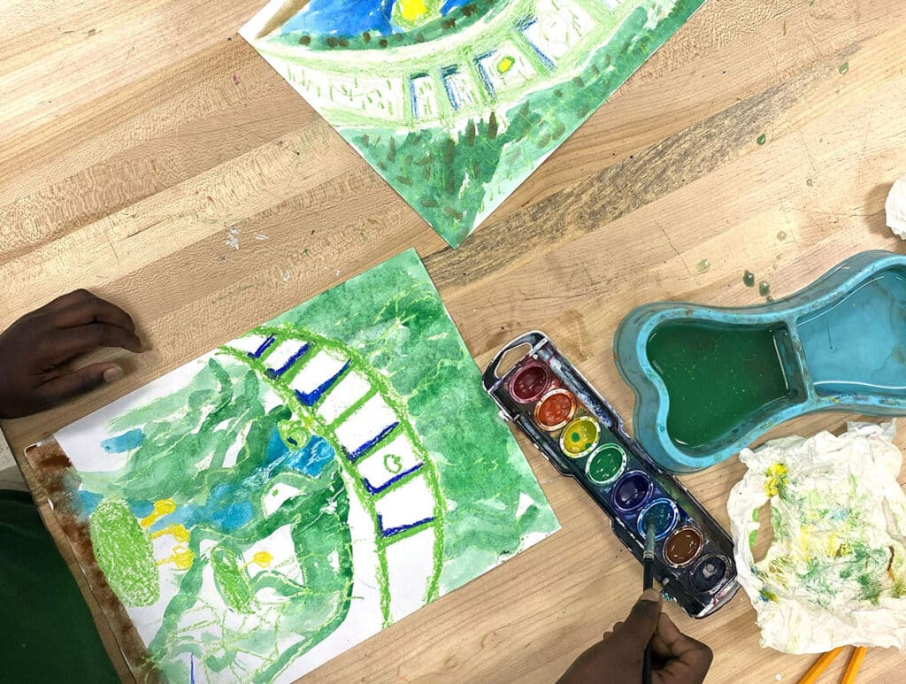 two watercolor paintings with student holding brush